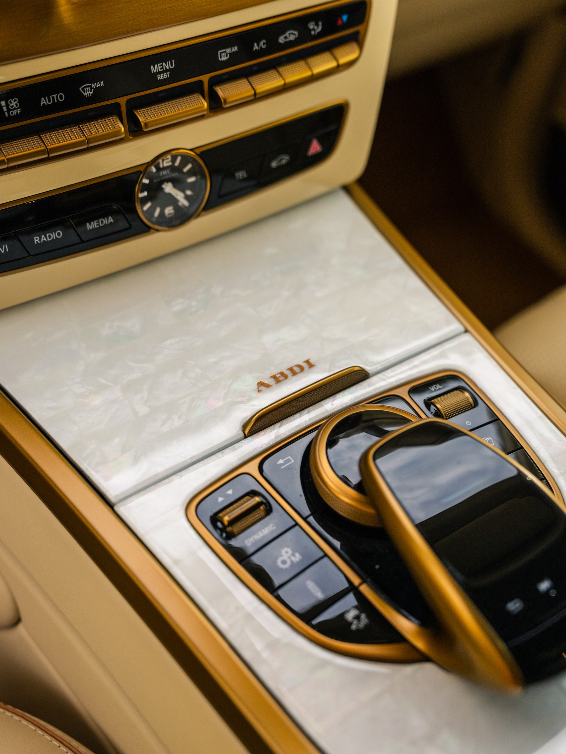 Center console — mother of pearl panel with ABDI branding, IWC analogue clock, custom gold-finished controls and trim