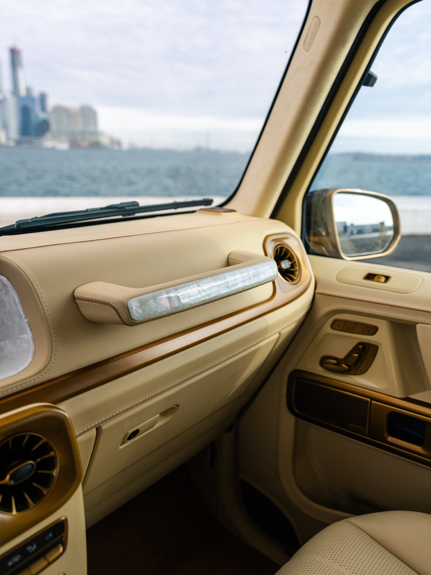 Mother of pearl integrated into the passenger handgrip — material crafts as functional element. Toronto skyline through the windshield