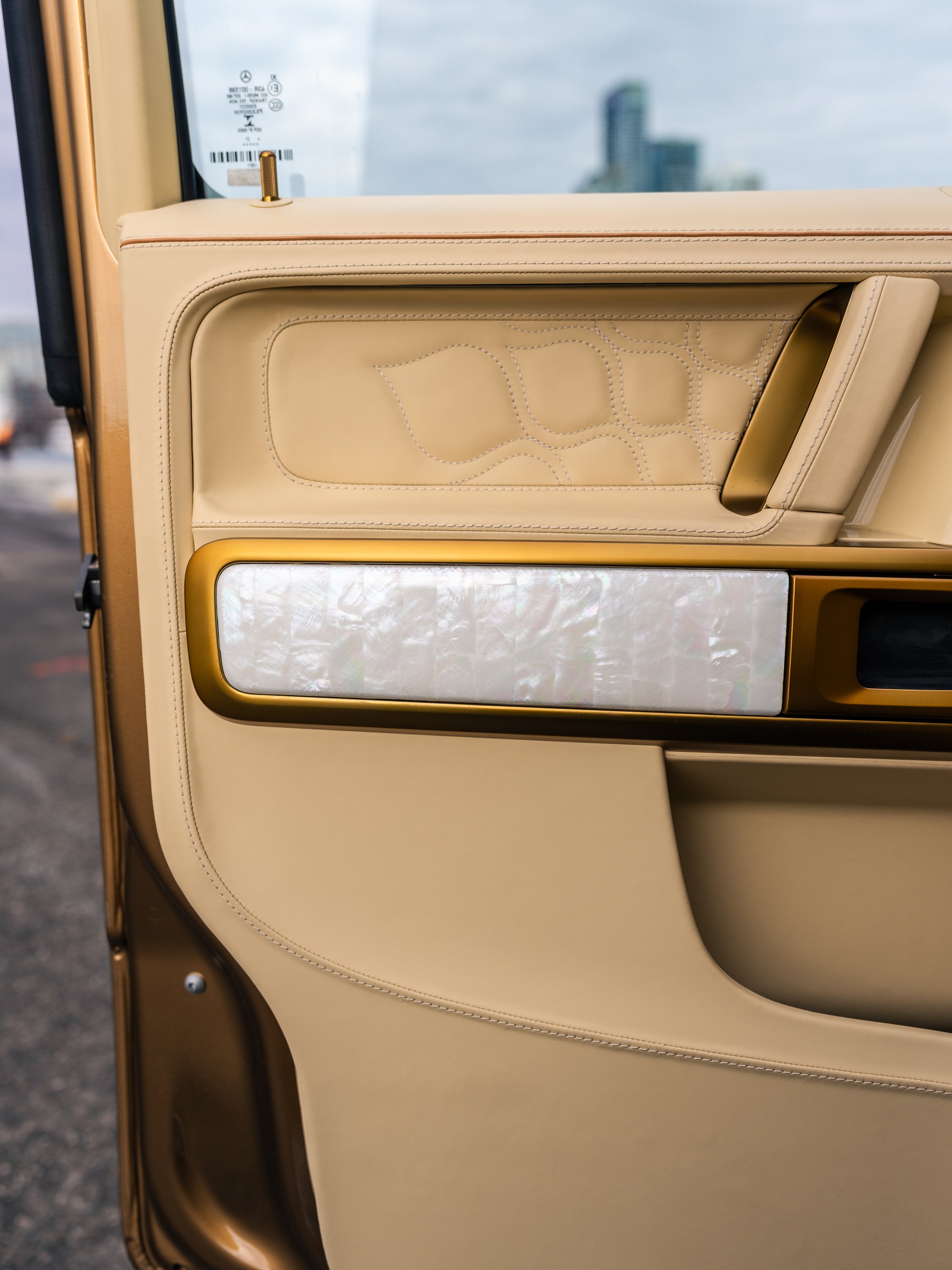 Hand-laid mother of pearl door panel framed in gold-finished trim, custom embroidered insert, Toronto skyline beyond