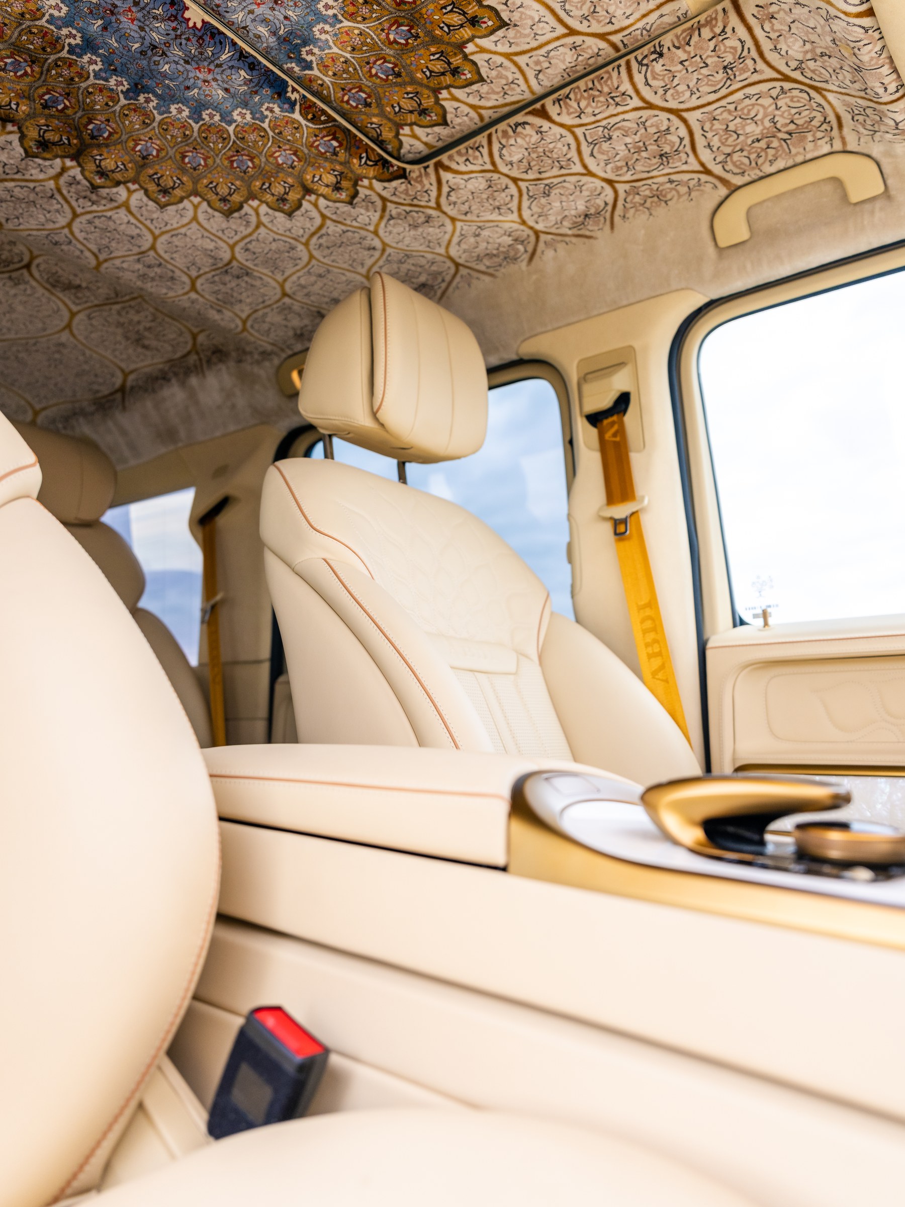 Front seat with custom embroidered backrest and ABDI gold seatbelt — Persian silk rug roofliner overhead
