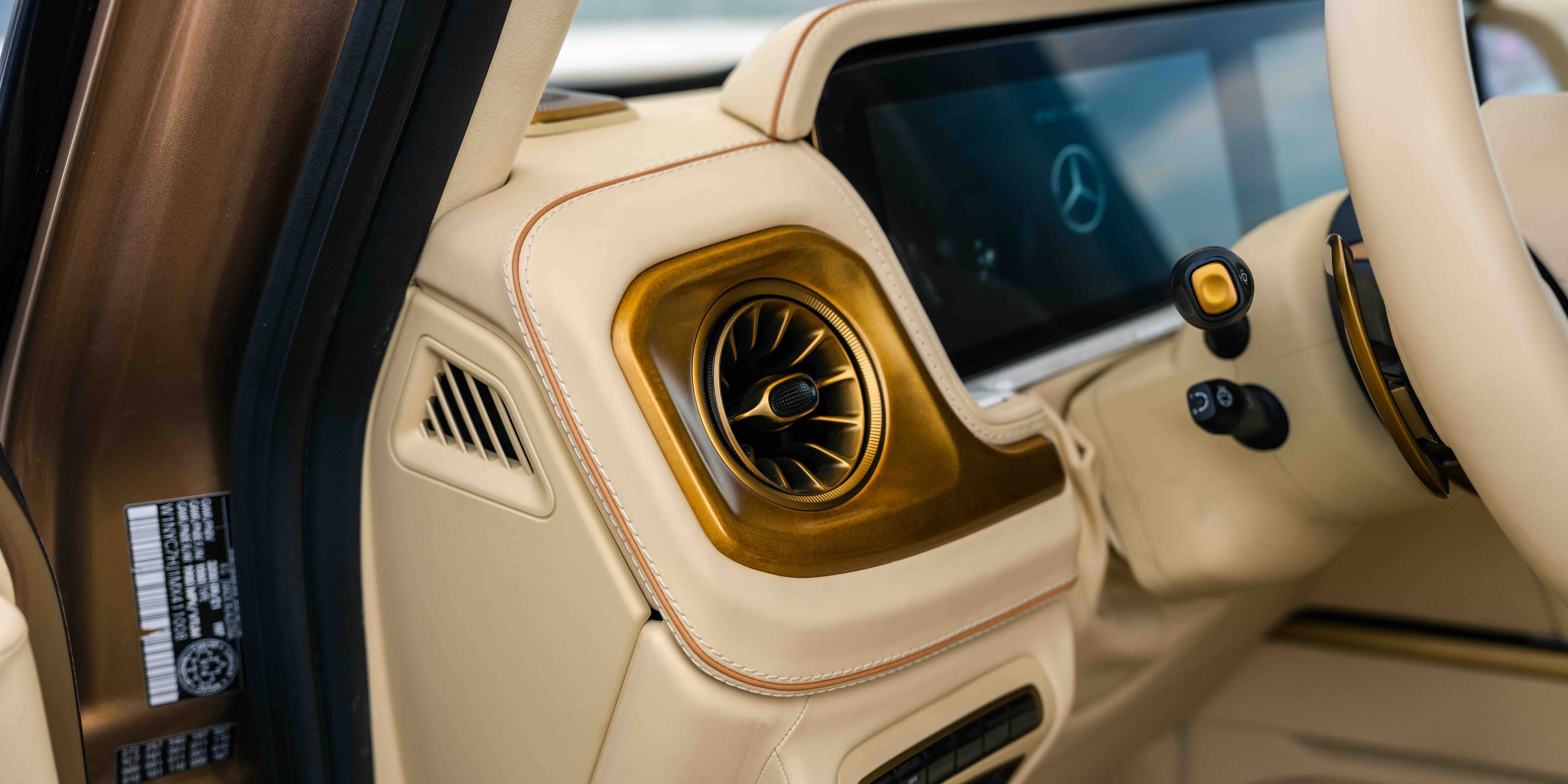 Sculptural air vent in custom gold surface treatment with leather piping — color-matched to the rug's gold field